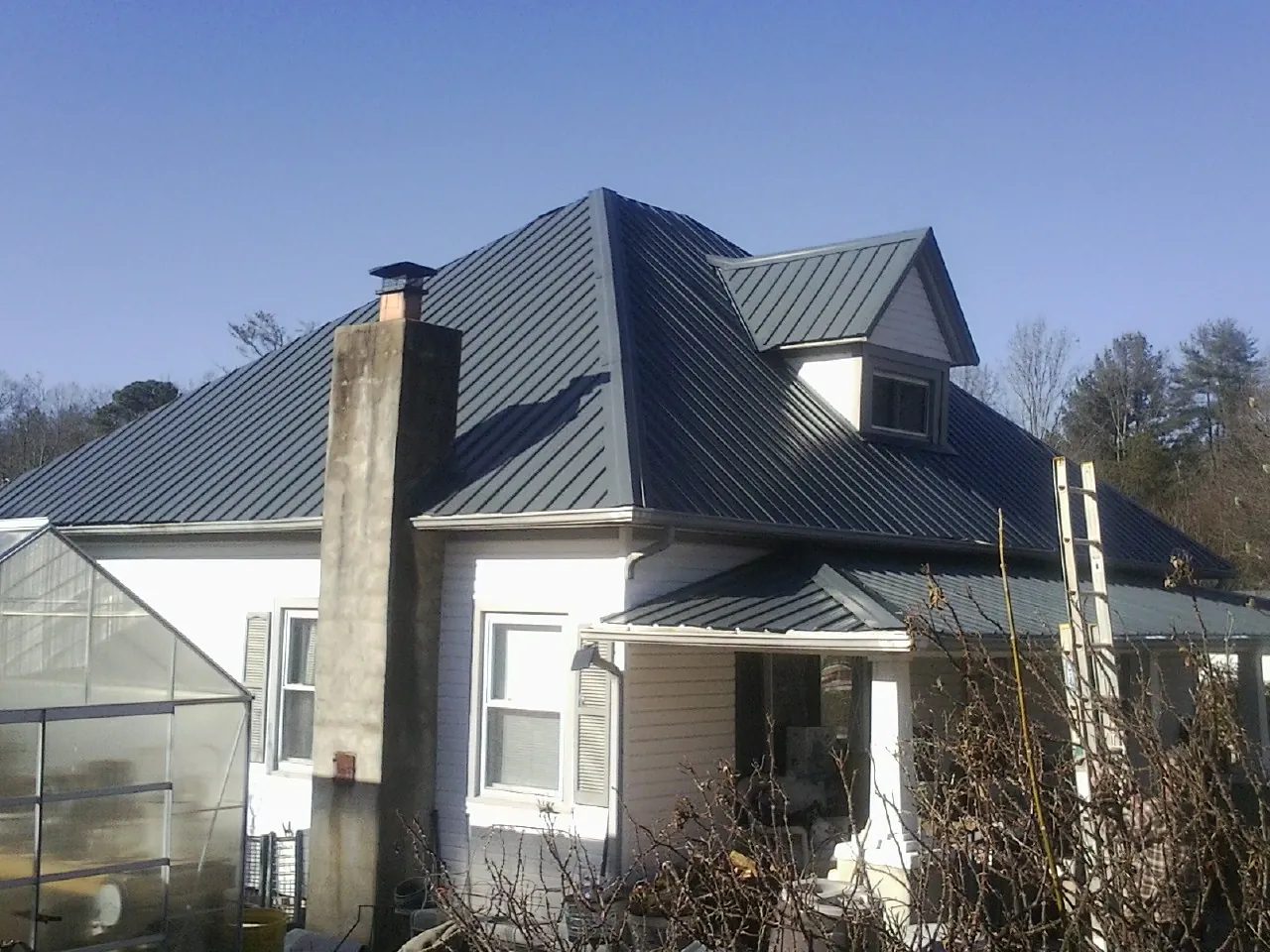 Dark blue standing seam metal roof on a white farmhouse with dormer — Slate & Tile Roof Repair by Roofing Brothers in Saint Paul Park