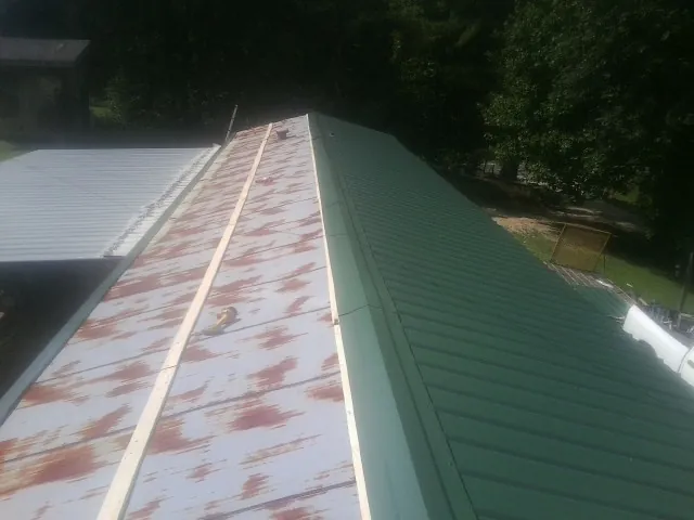 Old rusted panels beside newly installed green metal roofing — Wind Damage Roof Repair by Roofing Brothers in Saint Paul Park
