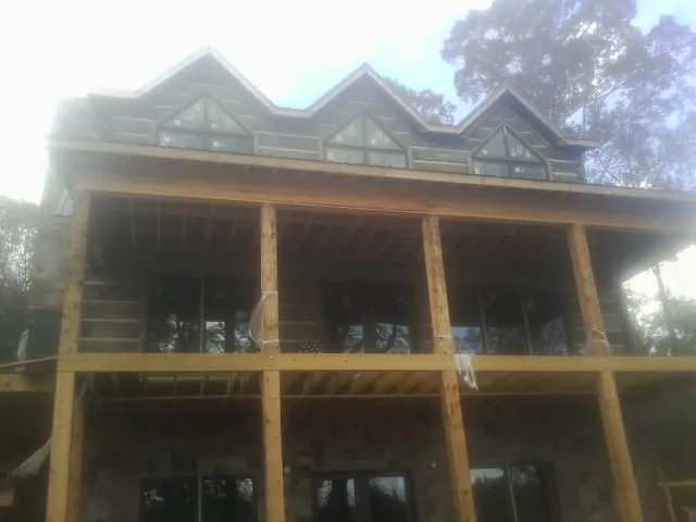 Dormers and porch framing on a large log home under construction — Roof Coating work by our crew in Saint Paul Park
