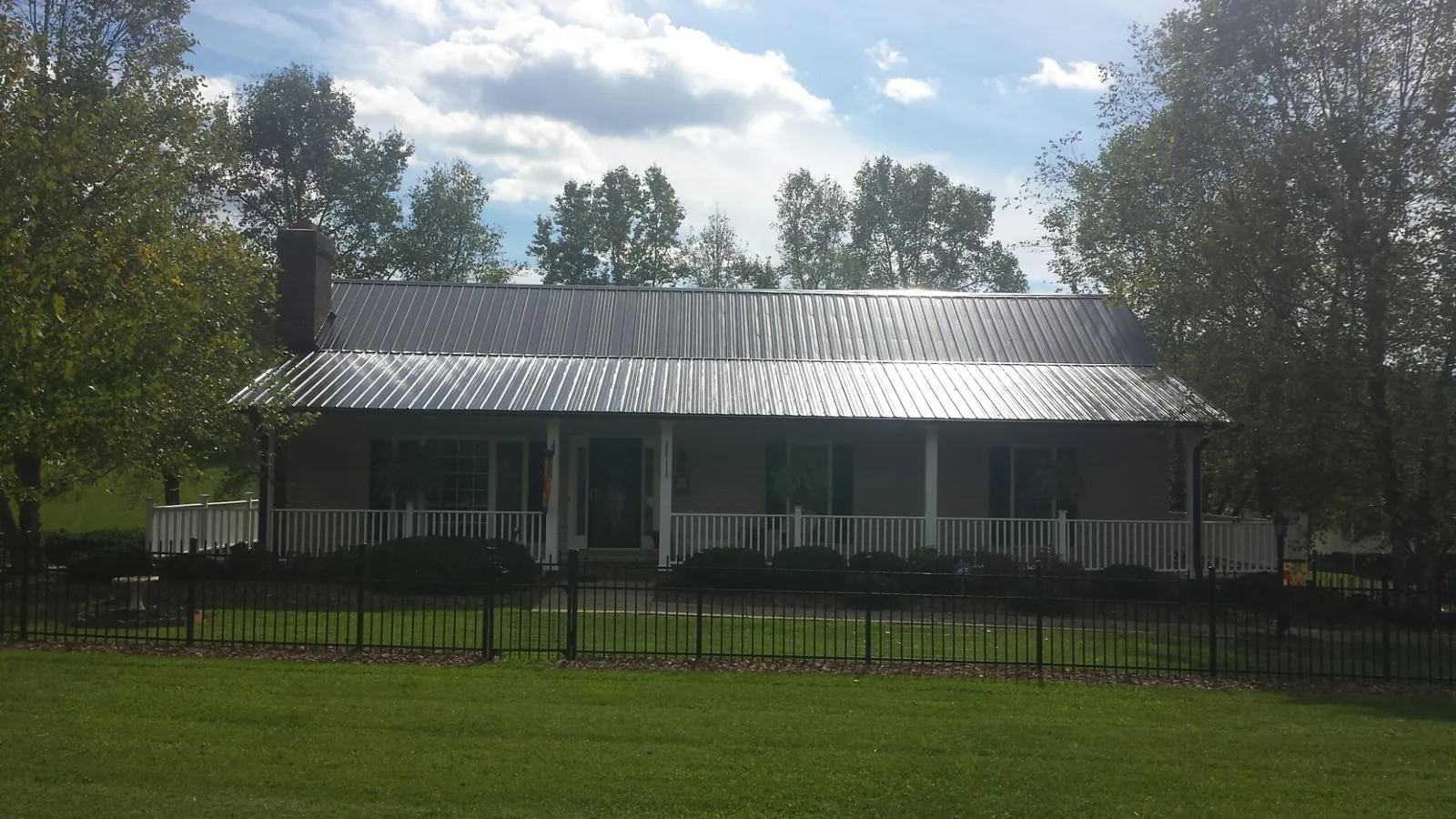 Gray metal roof on a brick ranch with a full width front porch — Gutter Guard Installation work by our crew in Saint Paul Park