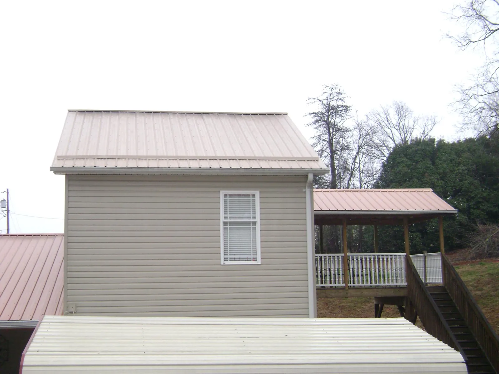 Tan metal roofs on a two story addition and attached porch, from a Roof Replacement job in Saint Paul Park