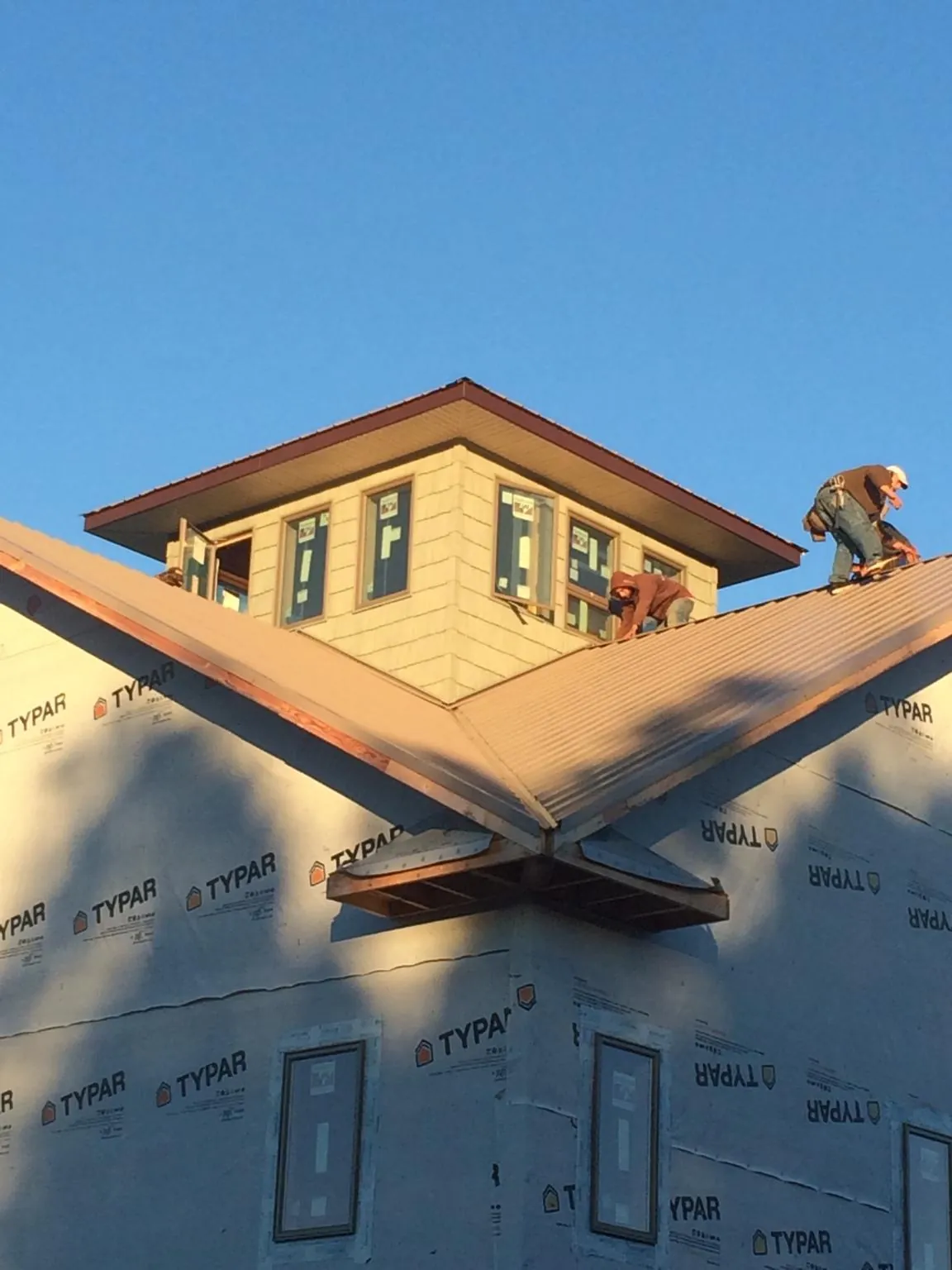 Roofers working around a rooftop cupola on a new metal roof at sunset — Roof Waterproofing in Saint Paul Park by Roofing Brothers